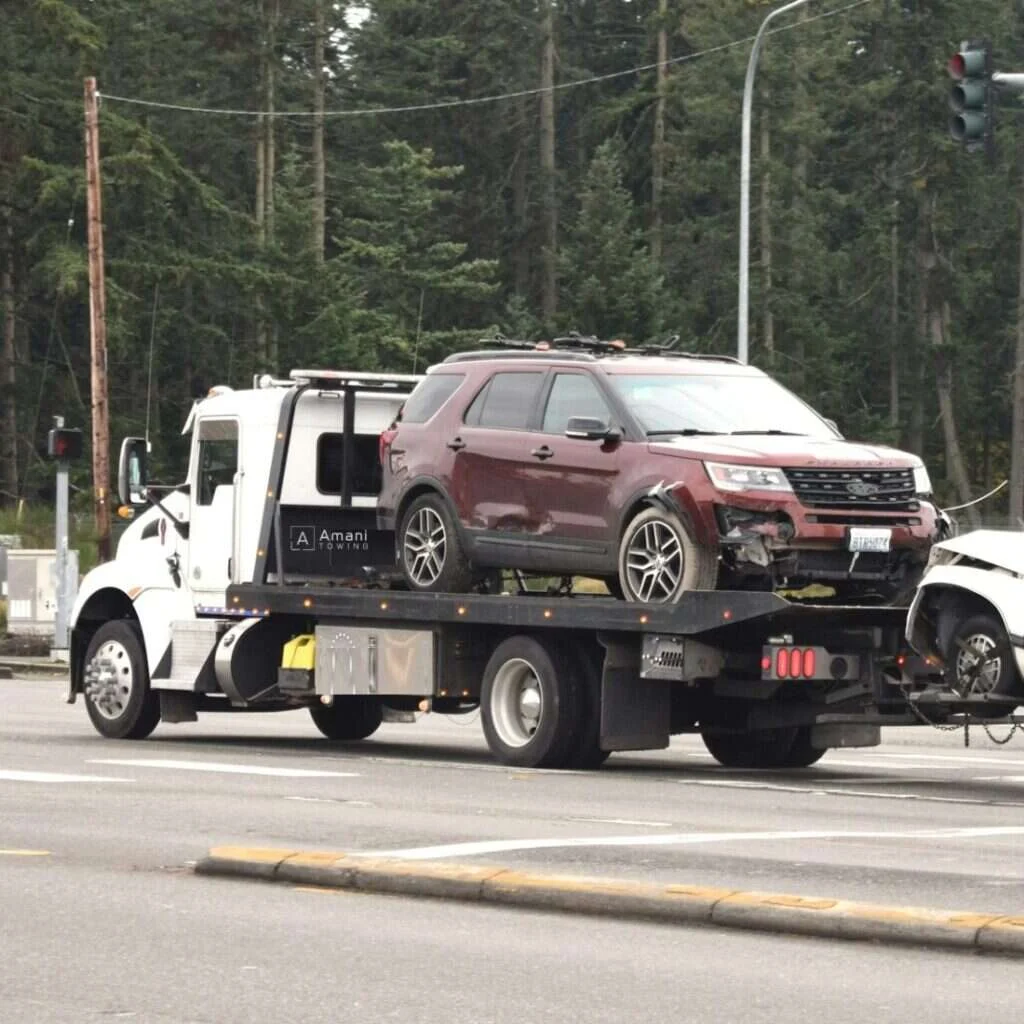 Amani Towing flatbed tow truck loaded with a customer vehicle