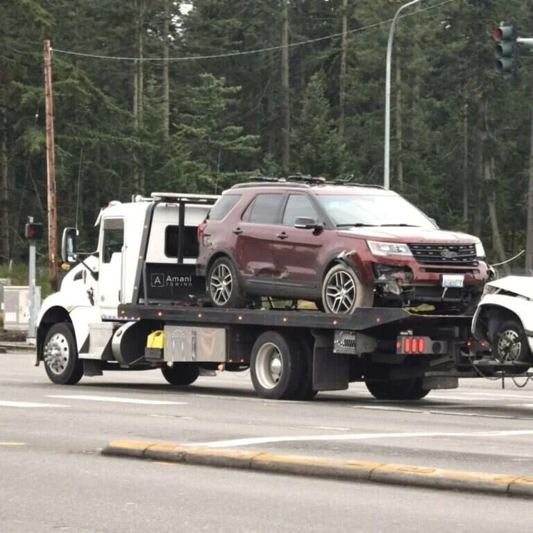 Amani Towing flatbed tow truck loaded with a customer vehicle